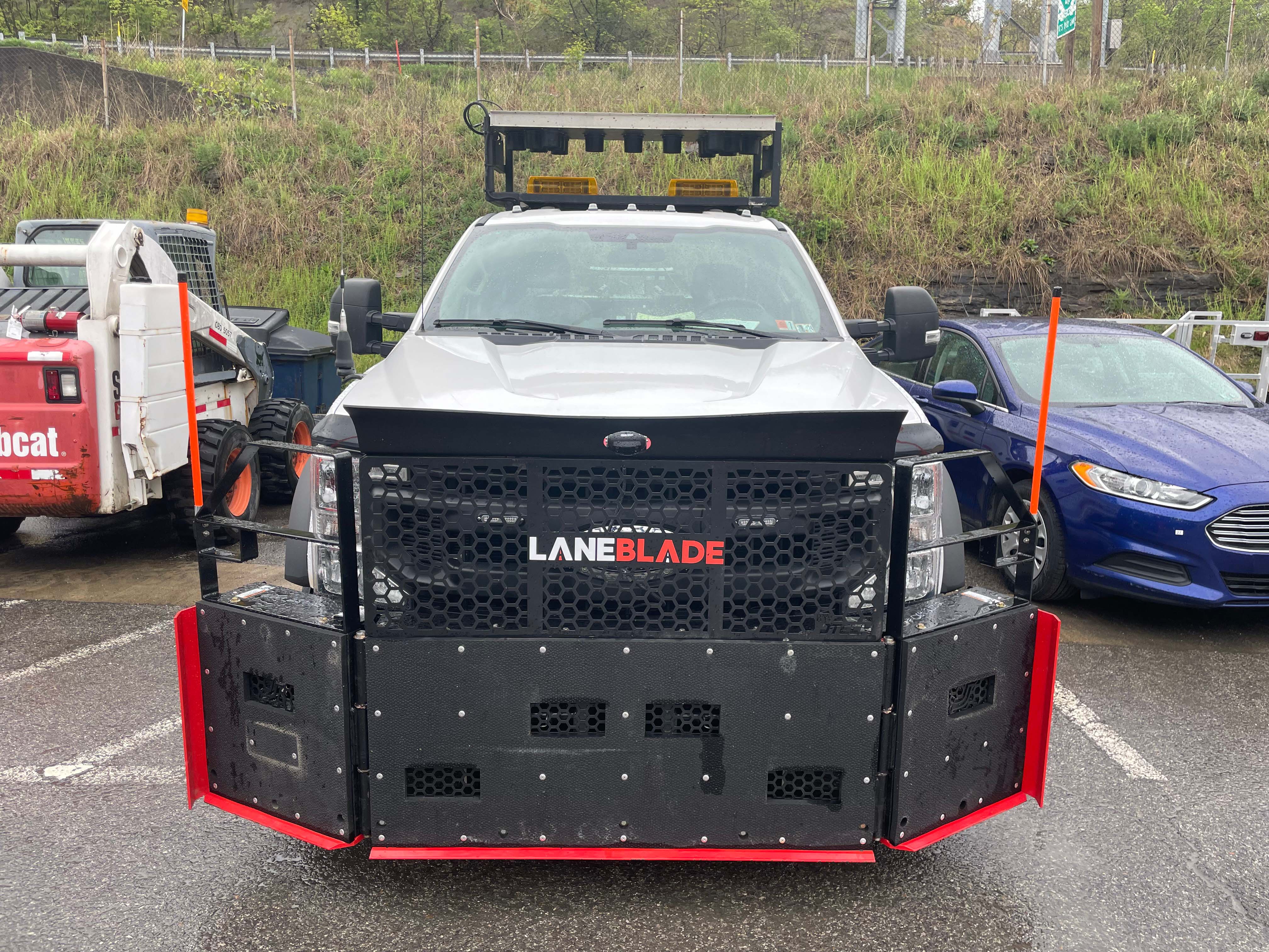 An image of the front of a PennDOT truck with a large black metal LaneBlade with red trim mounted to the front.